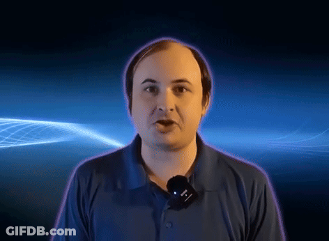 A Man In A Blue Shirt With A Microphone Around His Neck GIF