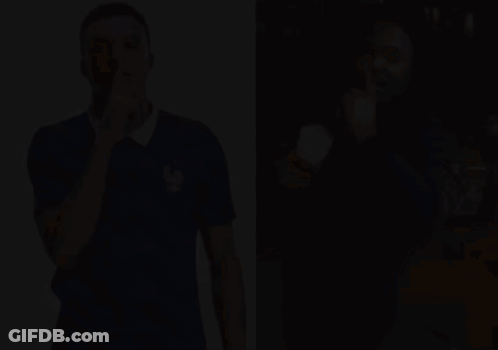 A Man In A Blue Shirt With A Rooster On It Holds His Finger To His Lips GIF
