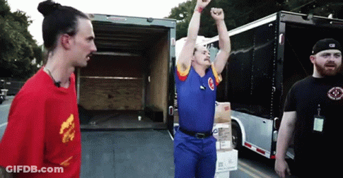 A Man In A Blue Shirt With The Letter C On It Is Standing In Front Of A Truck GIF