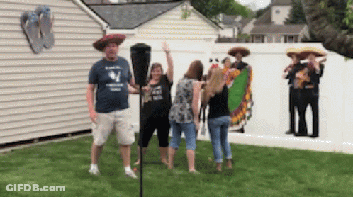 A Man In A Blue Shirt With The Letter W On It Stands Next To A Woman In A Sombrero GIF