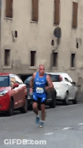 A Man In A Blue Shirt With The Number 55 On It Is Running Down The Street GIF