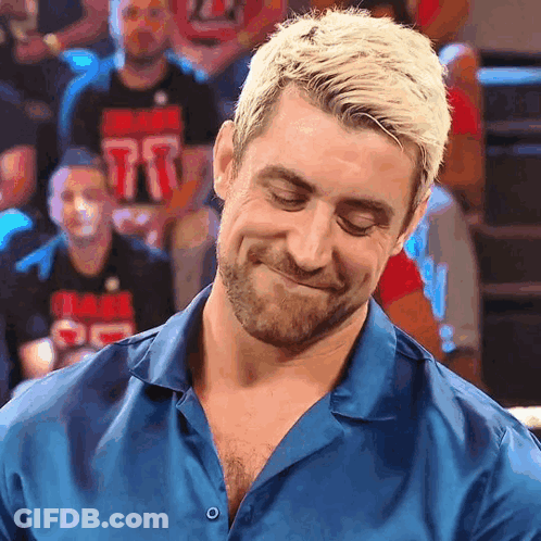 A Man In A Blue Shirt With The Number 77 On His Shirt Is Smiling GIF