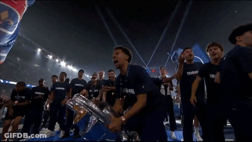 A Man In A Blue Shirt With The Word Trophe On It Holds A Trophy GIF
