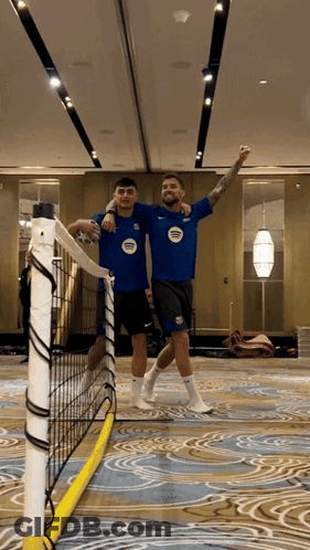 A Man In A Blue Shirt With The Word United On It Stands Next To Another Man In A Black Shirt GIF