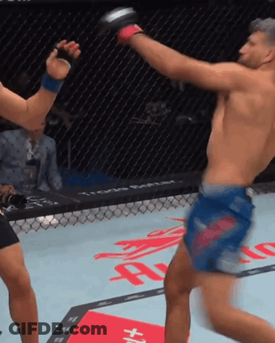 A Man In A Blue Shorts Kicks Another Man In A Cage GIF