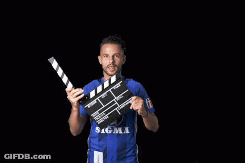 A Man In A Blue Sigma Shirt Is Holding A Clapper Board GIF