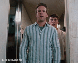 A Man In A Blue Striped Shirt Stands In A Hallway GIF