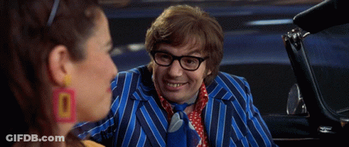 A Man In A Blue Striped Suit And Tie Is Talking To A Woman Wearing Earrings That Say 0 GIF