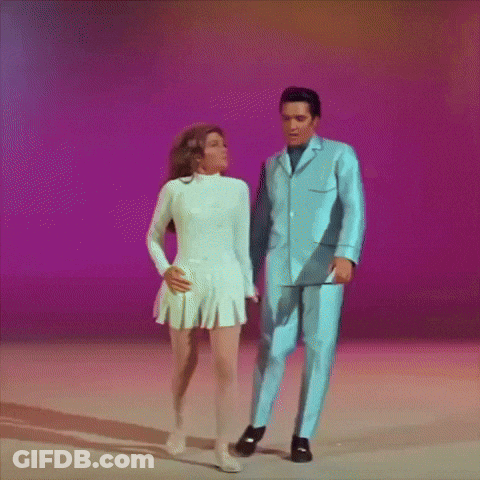 A Man In A Blue Suit And A Woman In A White Dress Are Dancing Together GIF