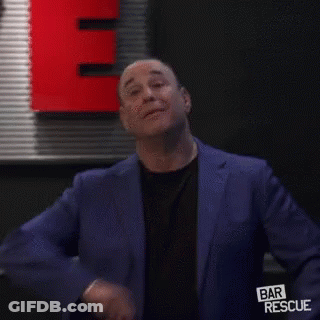 Man In Blue Suit And Black Shirt In Front Of Red Sign GIF