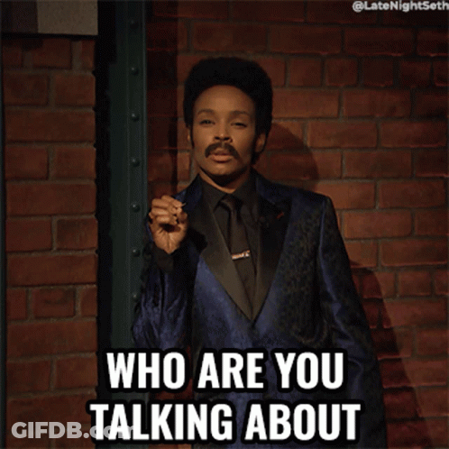 A Man In A Blue Suit And Black Tie Is Holding A Cigarette And Says Who Are You Talking About GIF