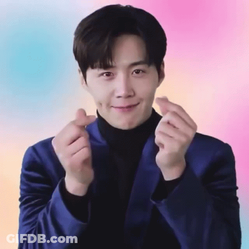 A Man In A Blue Suit And Black Turtleneck Is Making A Heart Shape With His Hands GIF