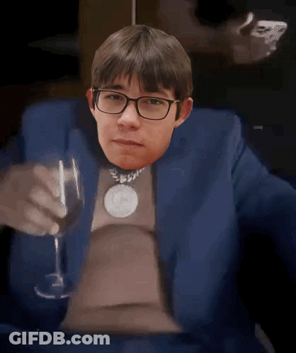 A Man In A Blue Suit And Glasses Is Holding A Wine Glass GIF