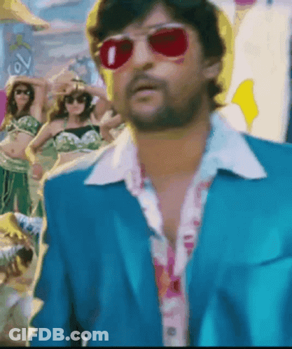 A Man In A Blue Suit And Red Sunglasses Is Standing In Front Of A Crowd GIF