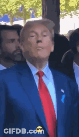 A Man In A Blue Suit And Red Tie Has A Smiley Face On His Shirt Pocket GIF