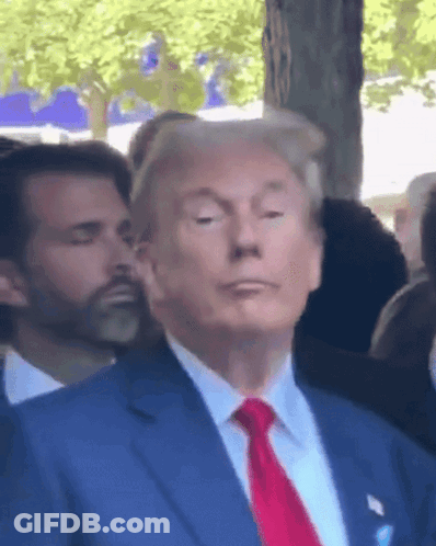 A Man In A Blue Suit And Red Tie Stands In Front Of A Crowd GIF