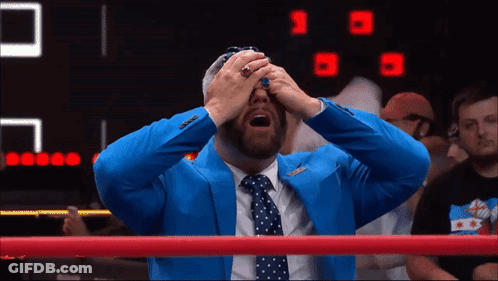 A Man In A Blue Suit And Tie Is Covering His Eyes GIF