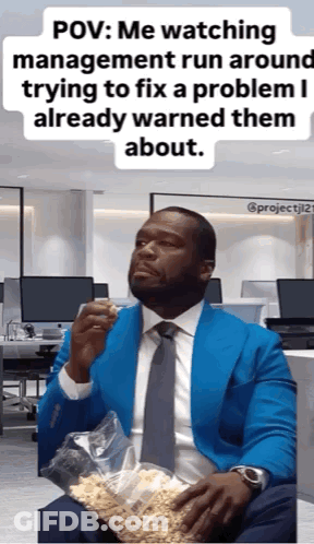 A Man In A Blue Suit And Tie Is Holding A Bag Of Popcorn .. GIF