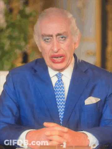 A Man In A Blue Suit And Tie Is Making A Funny Face With His Eyes Closed GIF