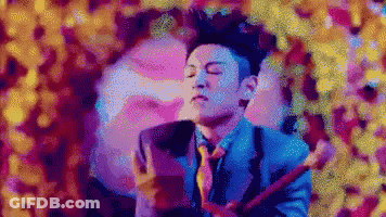 A Man In A Blue Suit And Tie Is Playing A Guitar GIF