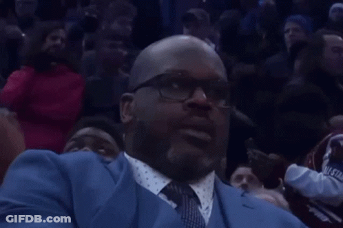 A Man In A Blue Suit And Tie Is Sitting In A Crowd Watching A Basketball Game GIF