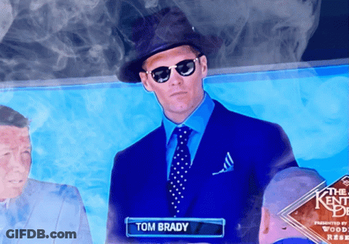 A Man In A Blue Suit And Tie With The Name Tom Brady GIF