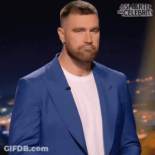 A Man In A Blue Suit And White Shirt Is Standing In Front Of A Sign That Says " Are You Smarter Than Celebrity " GIF