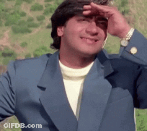 A Man In A Blue Suit Is Covering His Face With His Hand And Smiling . GIF