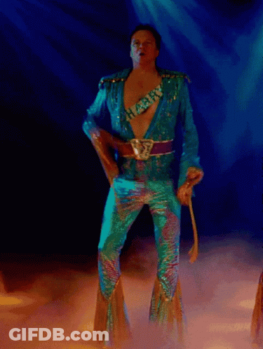 A Man In A Blue Suit Is Dancing In A Dark Room GIF