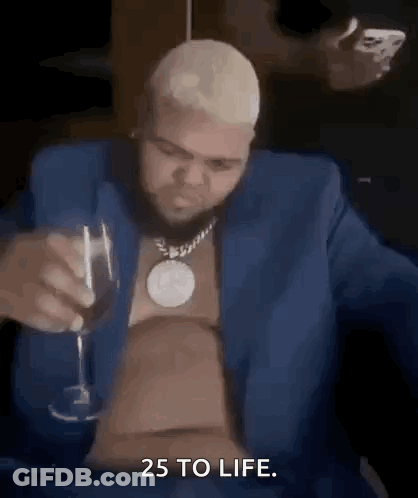 A Man In A Blue Suit Is Drinking A Glass Of Wine . GIF