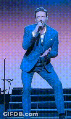 A Man In A Blue Suit Is Singing Into A Microphone On Stage GIF