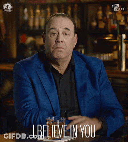 A Man In A Blue Suit Is Sitting At A Bar And Says I Believe In You GIF