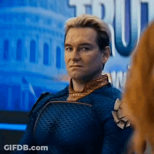 A Man In A Blue Suit Is Sitting In Front Of A Building And Looking At Another Man . GIF
