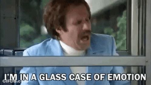 A Man In A Blue Suit Is Sitting In Front Of A Window With His Mouth Open . GIF