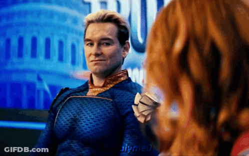 A Man In A Blue Suit Is Sitting Next To A Woman With Red Hair .. GIF