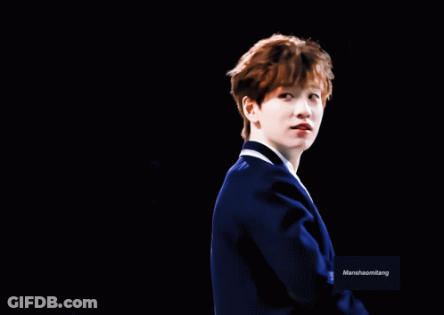 A Man In A Blue Suit Is Smiling In Front Of A Black Background With Marshhaomliang Written On It GIF