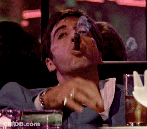 A Man In A Blue Suit Is Smoking A Cigar With Smoke Coming Out Of His Mouth GIF