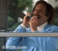A Man In A Blue Suit Is Smoking A Cigarette While Talking On A Cell Phone GIF