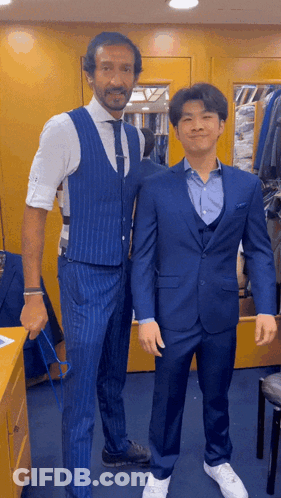 A Man In A Blue Suit Is Standing Next To Another Man In A White Shirt GIF