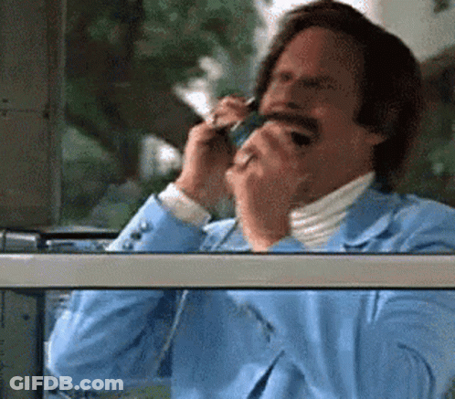A Man In A Blue Suit Is Talking On A Cellphone GIF