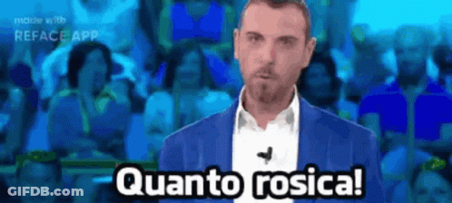 A Man In A Blue Suit Says Quanto Rosica In Front Of A Crowd Of People GIF