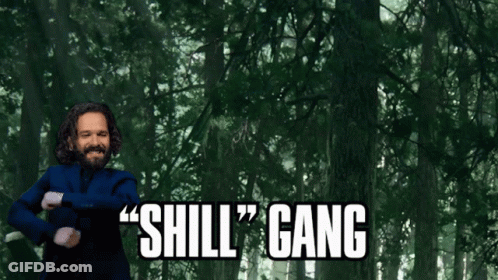 A Man In A Blue Suit Says " Shill Gang " In Front Of A Forest GIF