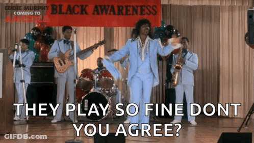 A Man In A Blue Suit Stands In Front Of A Band With A Sign That Says Black Awareness GIF