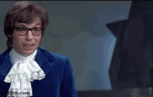 A Man In A Blue Suit Stands In Front Of A Green Sign That Says Gp GIF