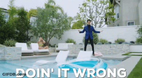 A Man In A Blue Suit Stands On A Raft In A Pool With The Words Doin ' It Wrong Below Him GIF