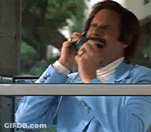 A Man In A Blue Suit Talks On A Cell Phone GIF