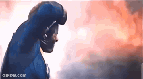 A Man In A Blue Superhero Costume Is Standing In Front Of A Burning Building GIF