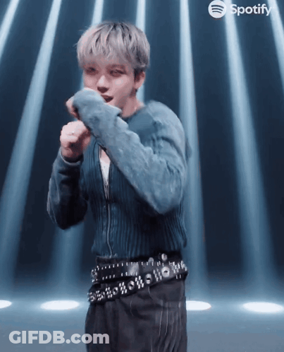 A Man In A Blue Sweater And Black Pants Is Dancing In Front Of Spotify GIF