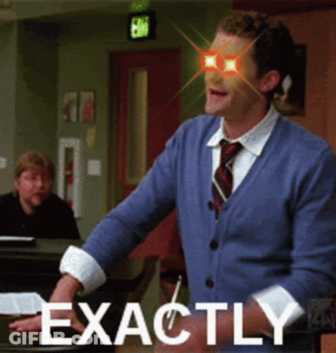 Man In Blue Sweater And Tie Standing By Piano GIF