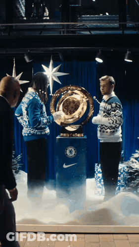 A Man In A Blue Sweater Holds A Trophy With The Chelsea Logo On It GIF